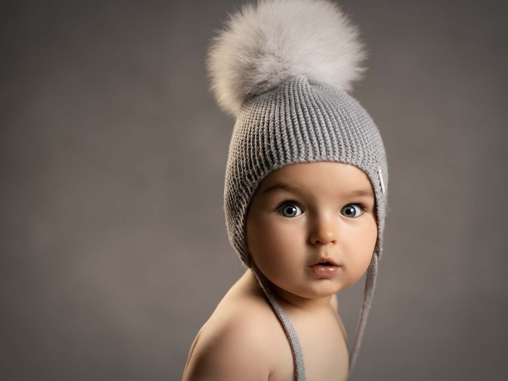 Niño y su gorro Marco posando junto a su gorro en su sesión infantil.