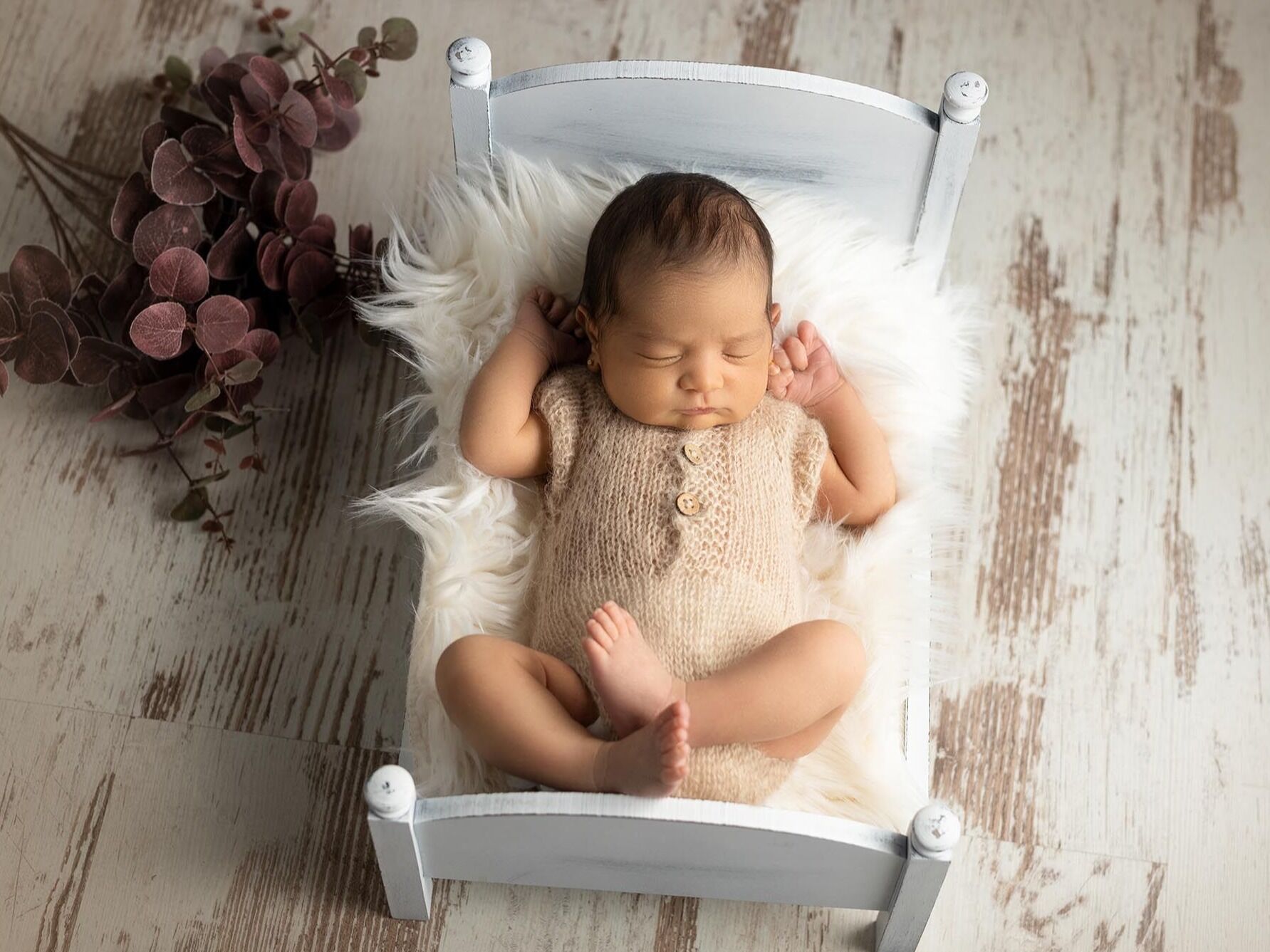 Bebé en su cama Bebé dormido en una pequeña cama para su sesión newborn.