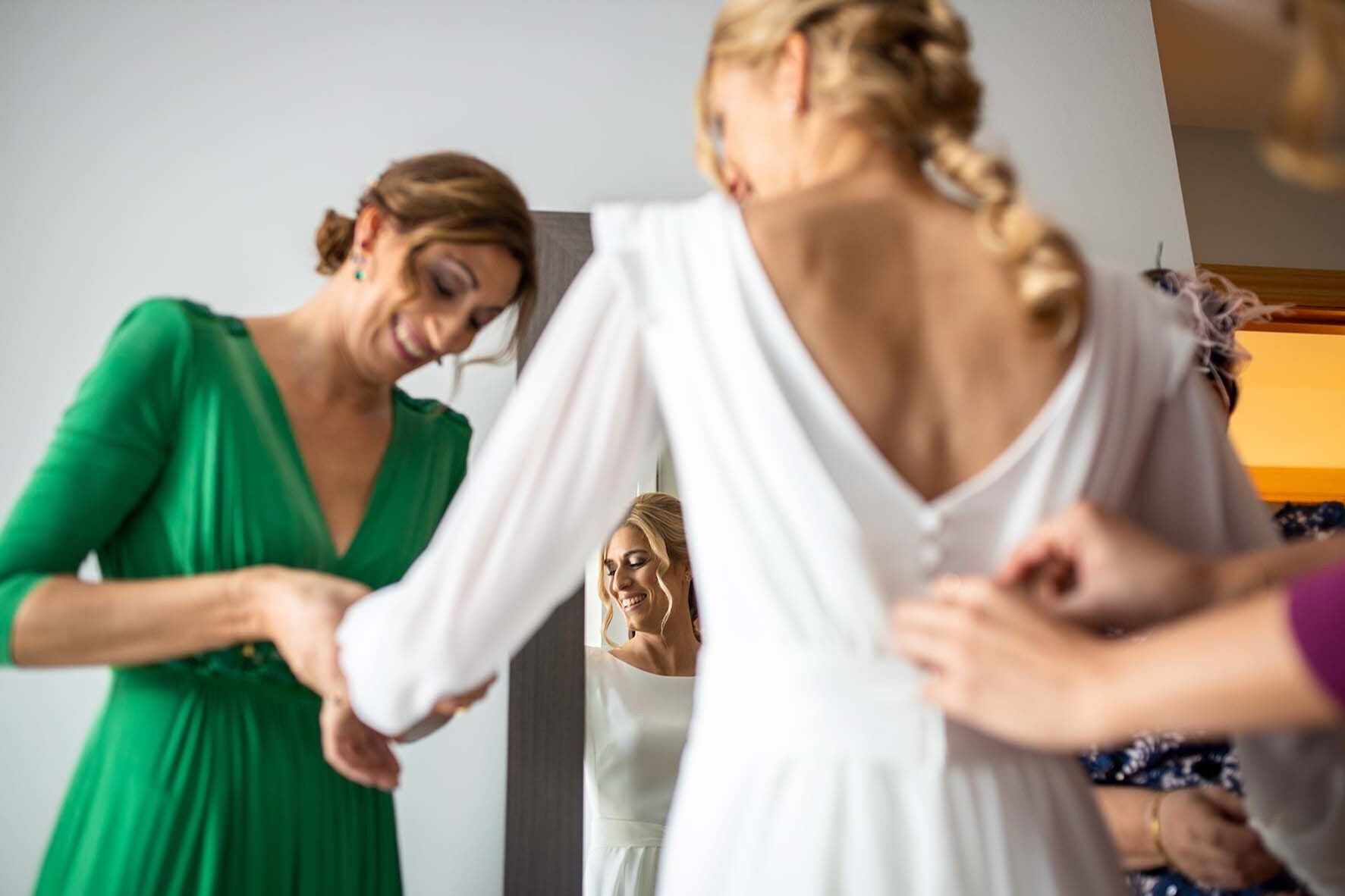 Preparativos de la novia Raquel comenzando a vestirse el día de su boda en su casa junto a su familia.